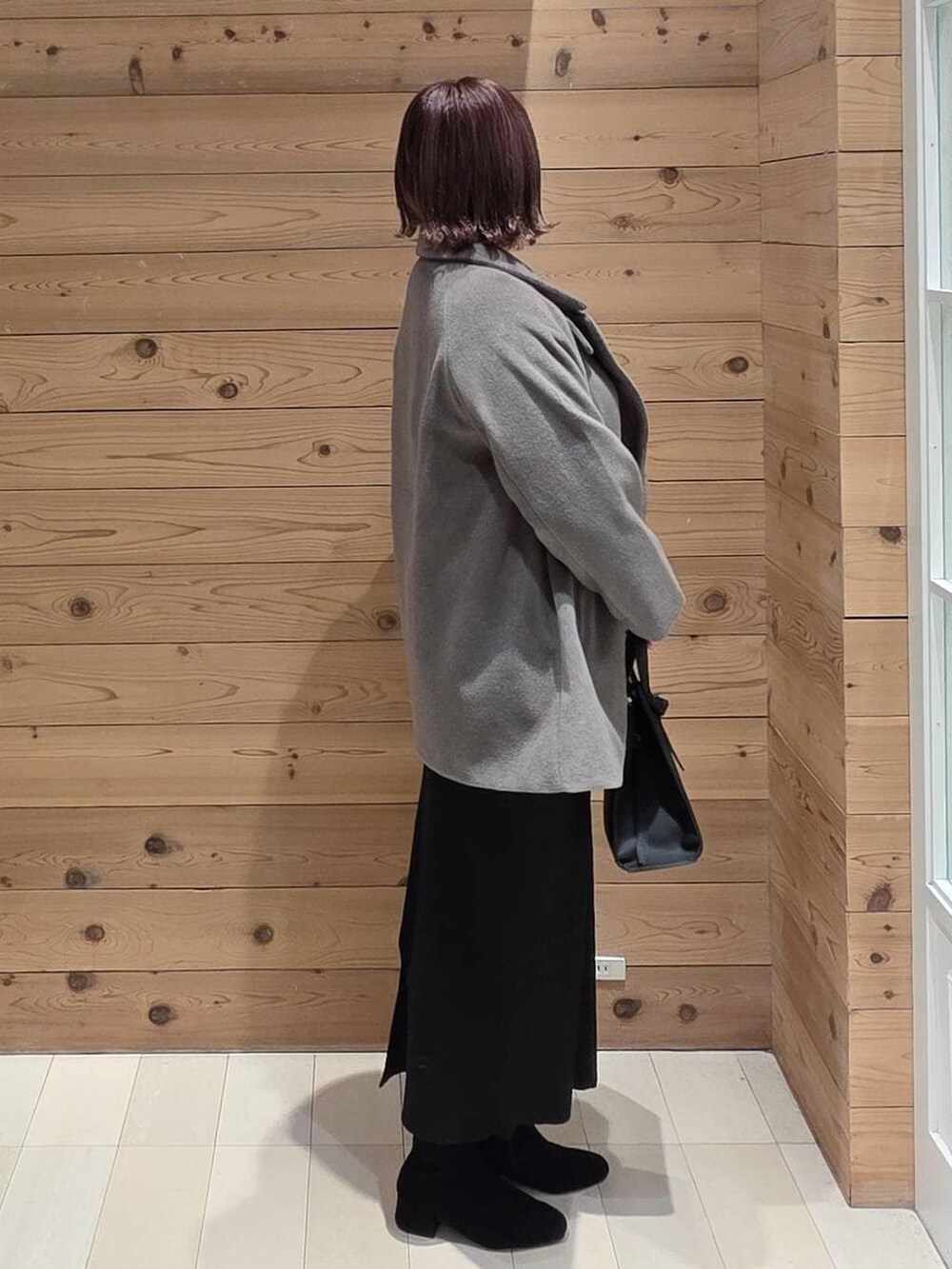 ブラック系のショルダーバッグ、ブラウン系のチェスターコート、ホワイト系のTシャツ/カットソーを着用したレディースの冬コーディネートの2枚目の写真