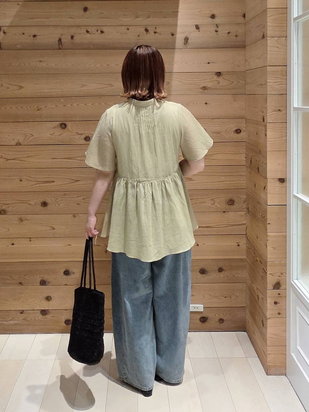 ブルー系のデニムパンツ、ホワイト系のタンクトップ、ブラック系のクラッチバッグを着用したレディースの夏コーディネートの3枚目の写真
