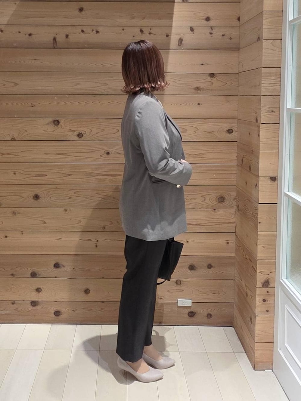 ホワイト系のパンプス、ブラック系のスラックス、ブラック系のトートバッグを着用したレディースの春コーディネートの2枚目の写真