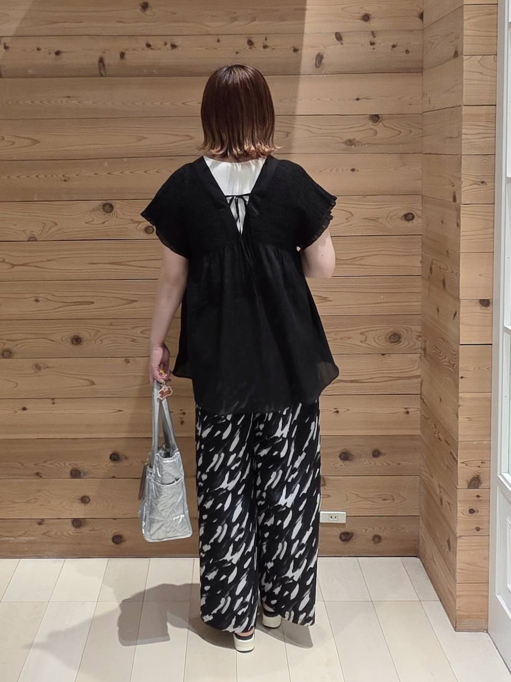 シルバー系のトートバッグ、ブルー系のその他パンツ、ホワイト系のタンクトップを着用したレディースの夏コーディネートの3枚目の写真