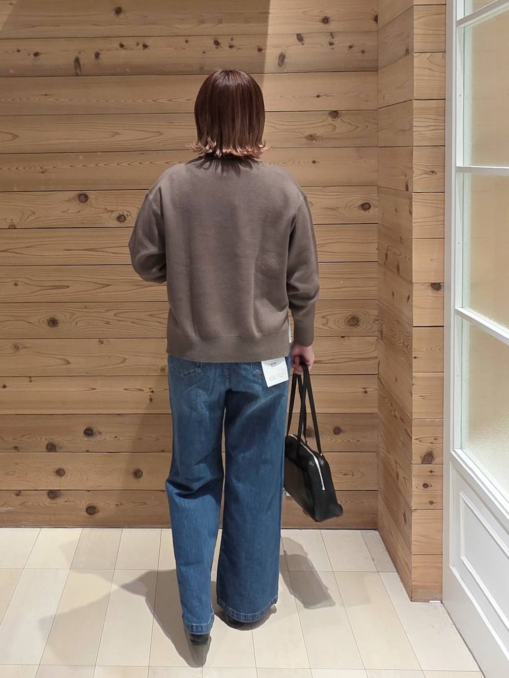 ブラック系のバレエシューズ、ブルー系のデニムパンツ、ブラウン系のニット/セーターを着用したレディースの春コーディネートの3枚目の写真