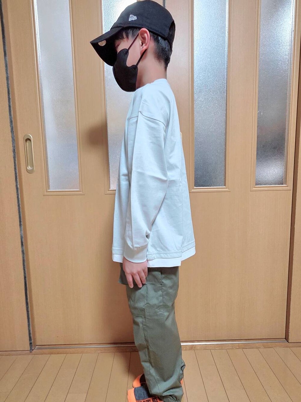 グリーン系のカーゴパンツ、グレー系のTシャツ/カットソー、ブラック系のキャップを着用したキッズの秋コーディネートの2枚目の写真