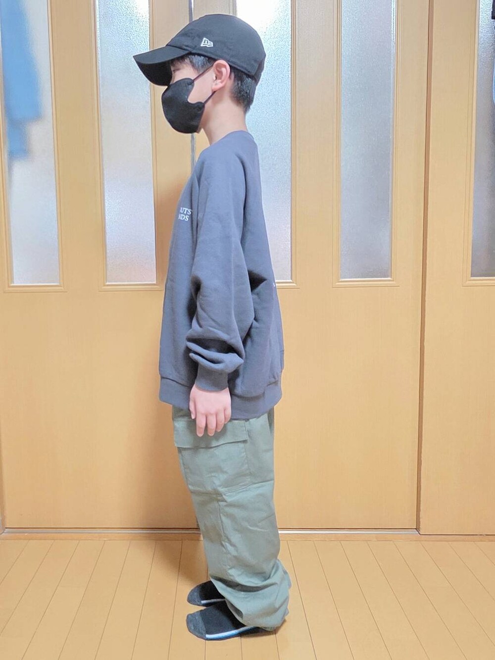 グリーン系のカーゴパンツ、グレー系のスウェット、ブラック系のキャップを着用したキッズの秋コーディネートの2枚目の写真
