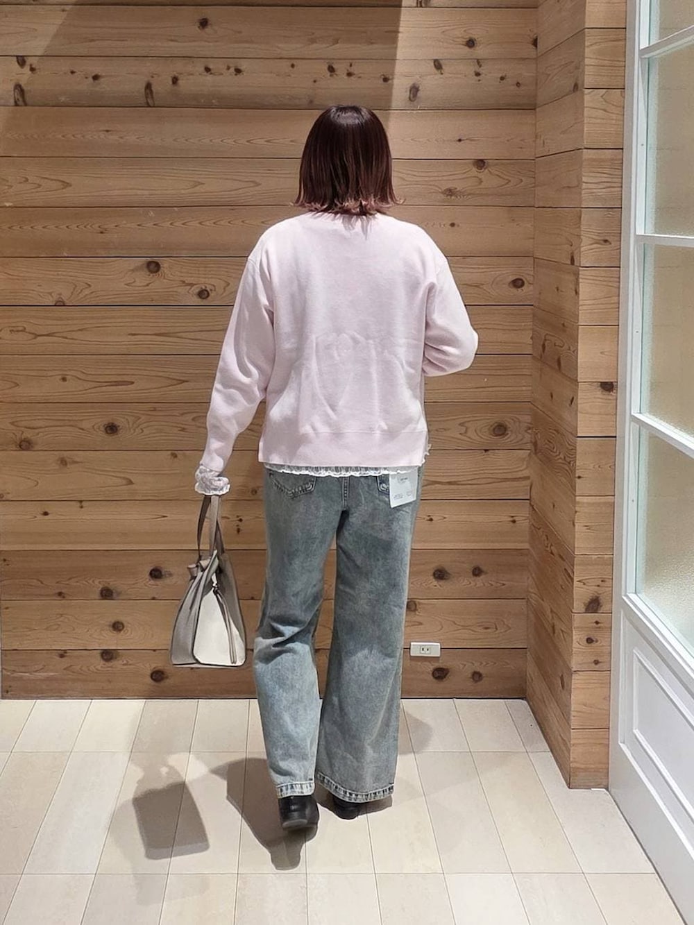 ブラック系のローファー、ホワイト系のショルダーバッグ、ブルー系のデニムパンツを着用したレディースの冬コーディネートの3枚目の写真