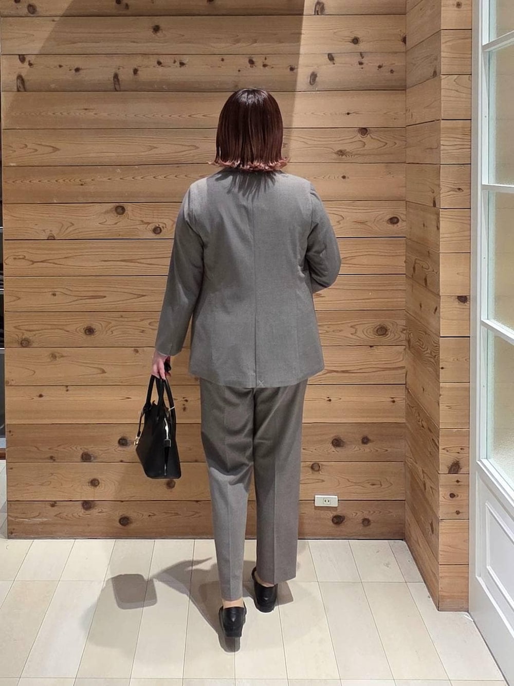 ブラック系のローファー、ブラック系のショルダーバッグ、ブラウン系のスラックスを着用したレディースの冬コーディネートの3枚目の写真