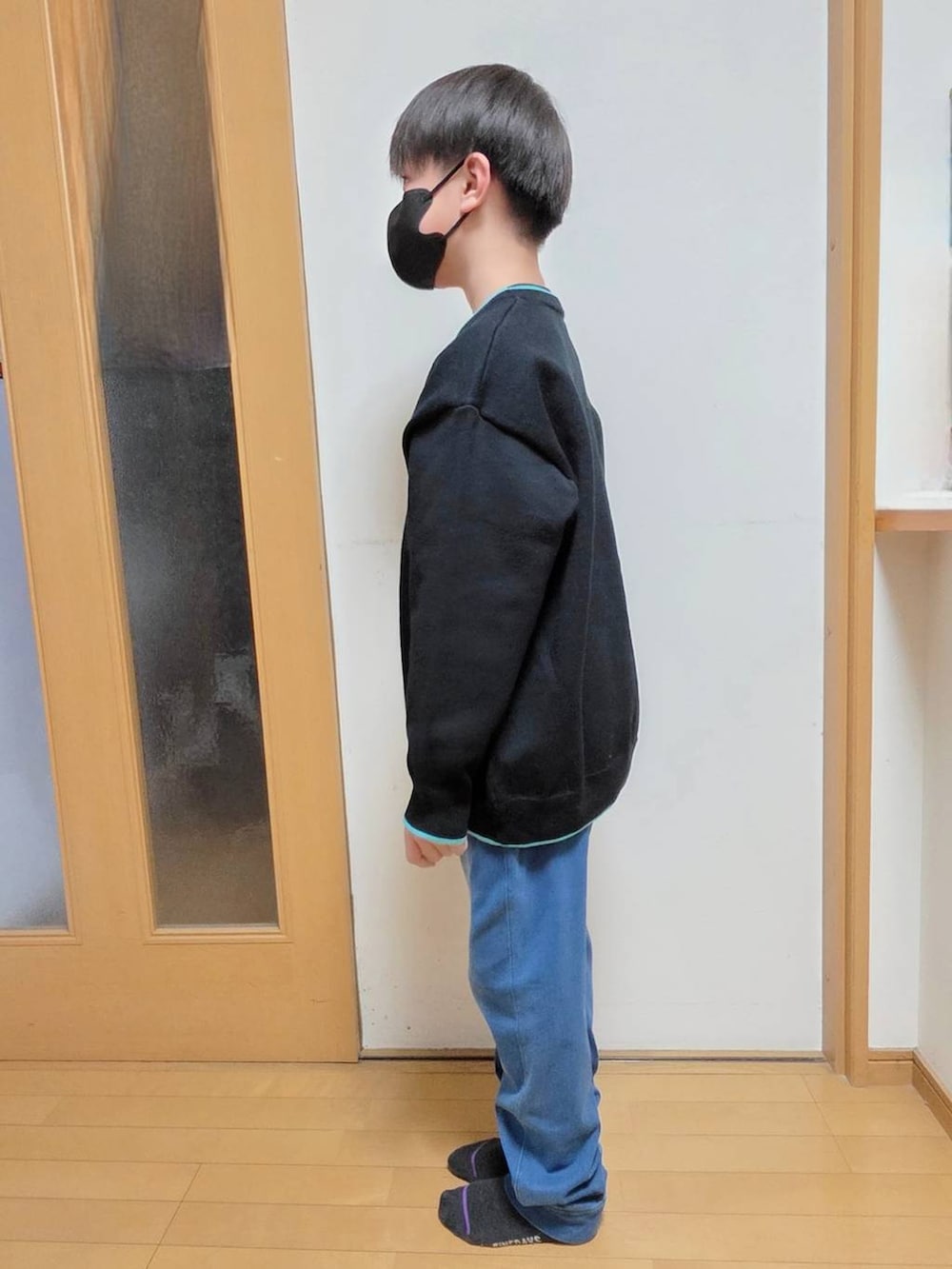 ブラック系のTシャツ/カットソー、ブルー系のデニムパンツ、ブラック系のニット/セーターを着用したキッズの冬コーディネートの2枚目の写真