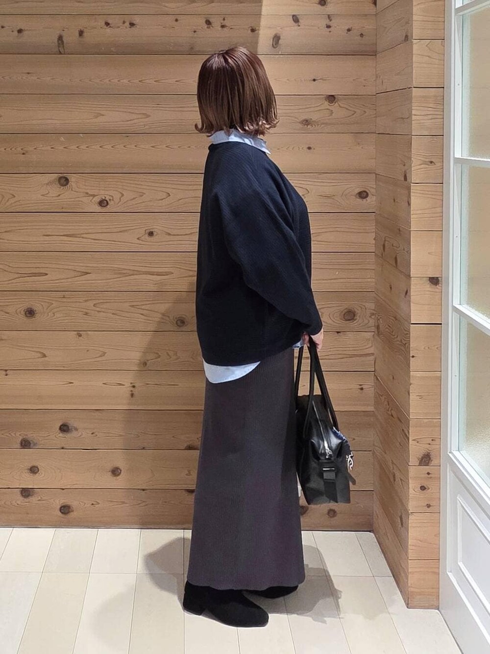 ブラック系のボストンバッグ、ブラウン系のチェスターコート、ブルー系のシャツ/ブラウスを着用したレディースの冬コーディネートの2枚目の写真