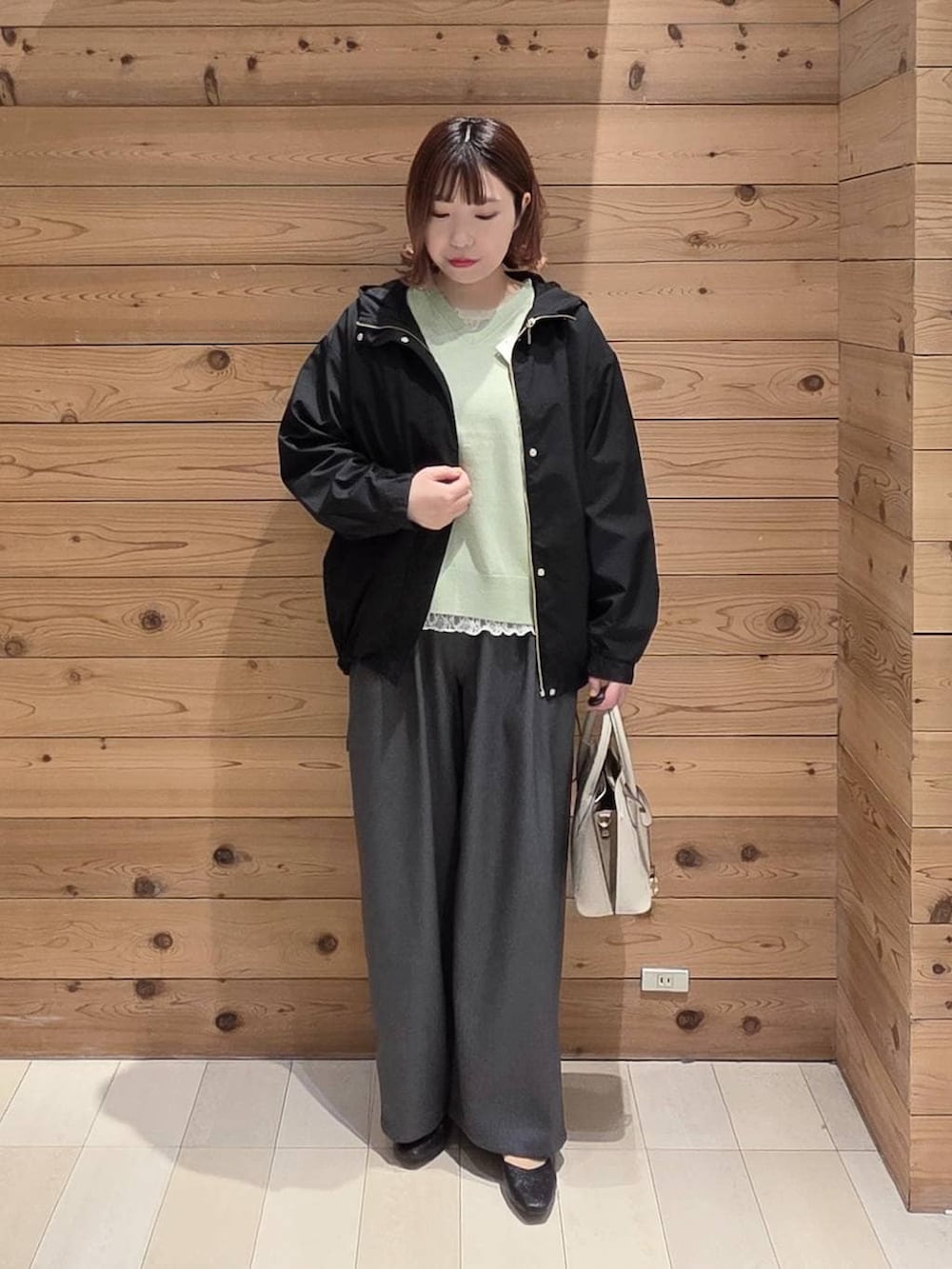 ブラック系のパンプス、ホワイト系のショルダーバッグ、ブラック系のマウンテンパーカーを着用したレディースの春コーディネートの4枚目の写真