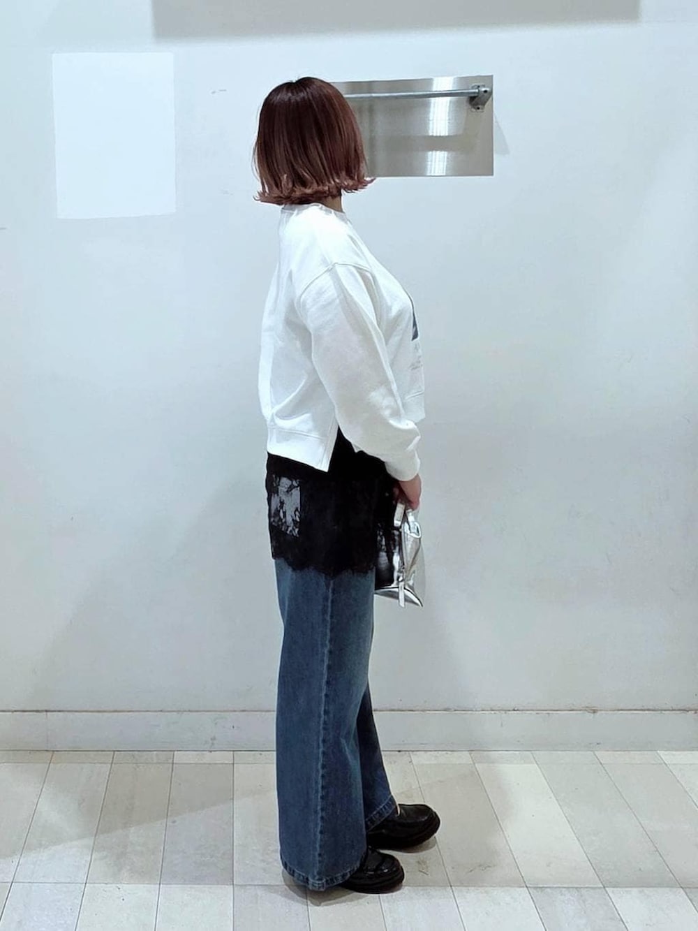 シルバー系のショルダーバッグ、ブラック系のローファー、ブルー系のデニムパンツを着用したレディースの春コーディネートの2枚目の写真