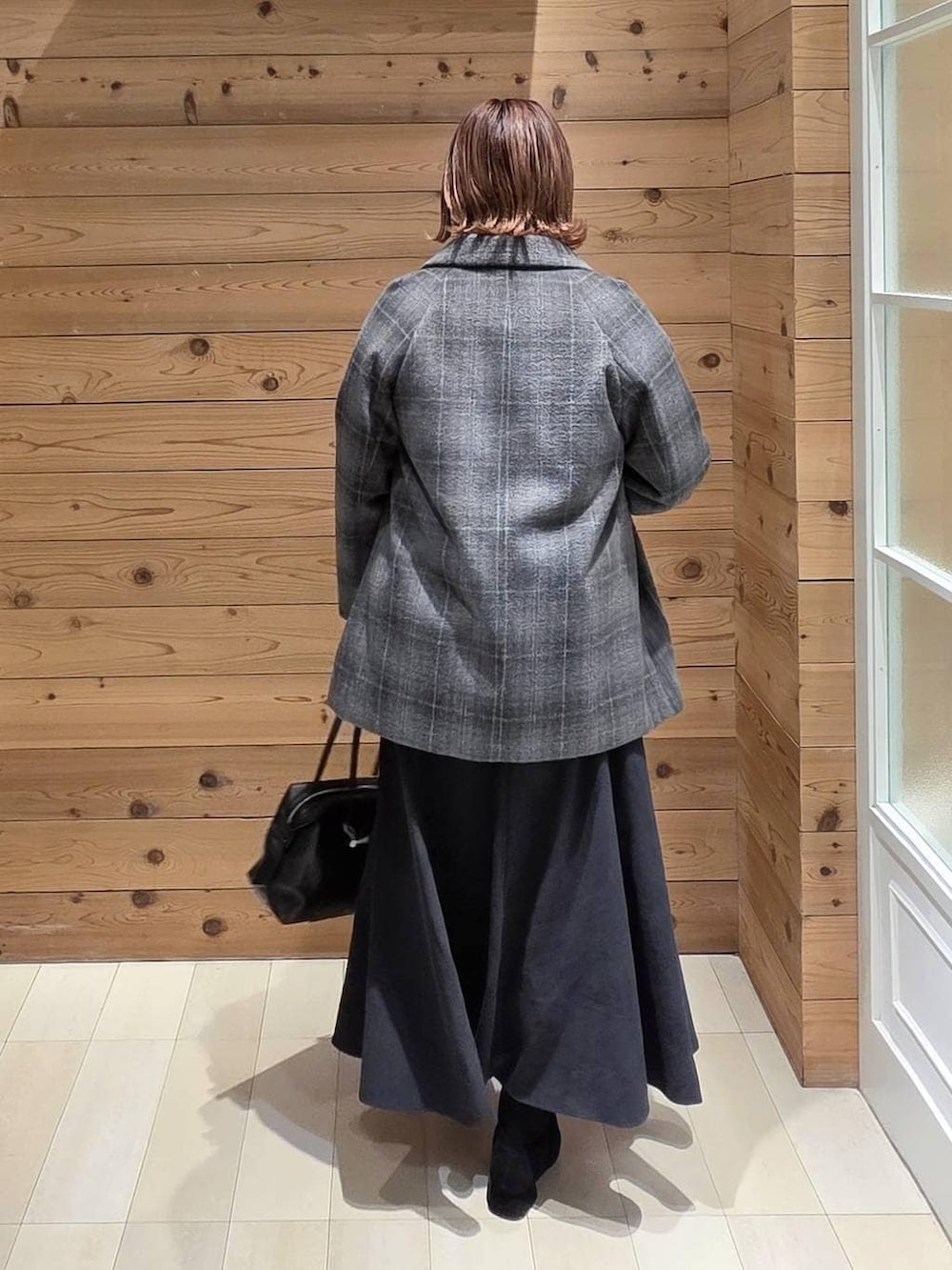 ブラック系のボストンバッグ、その他のチェスターコート、グレー系のスカートを着用したレディースの冬コーディネートの3枚目の写真