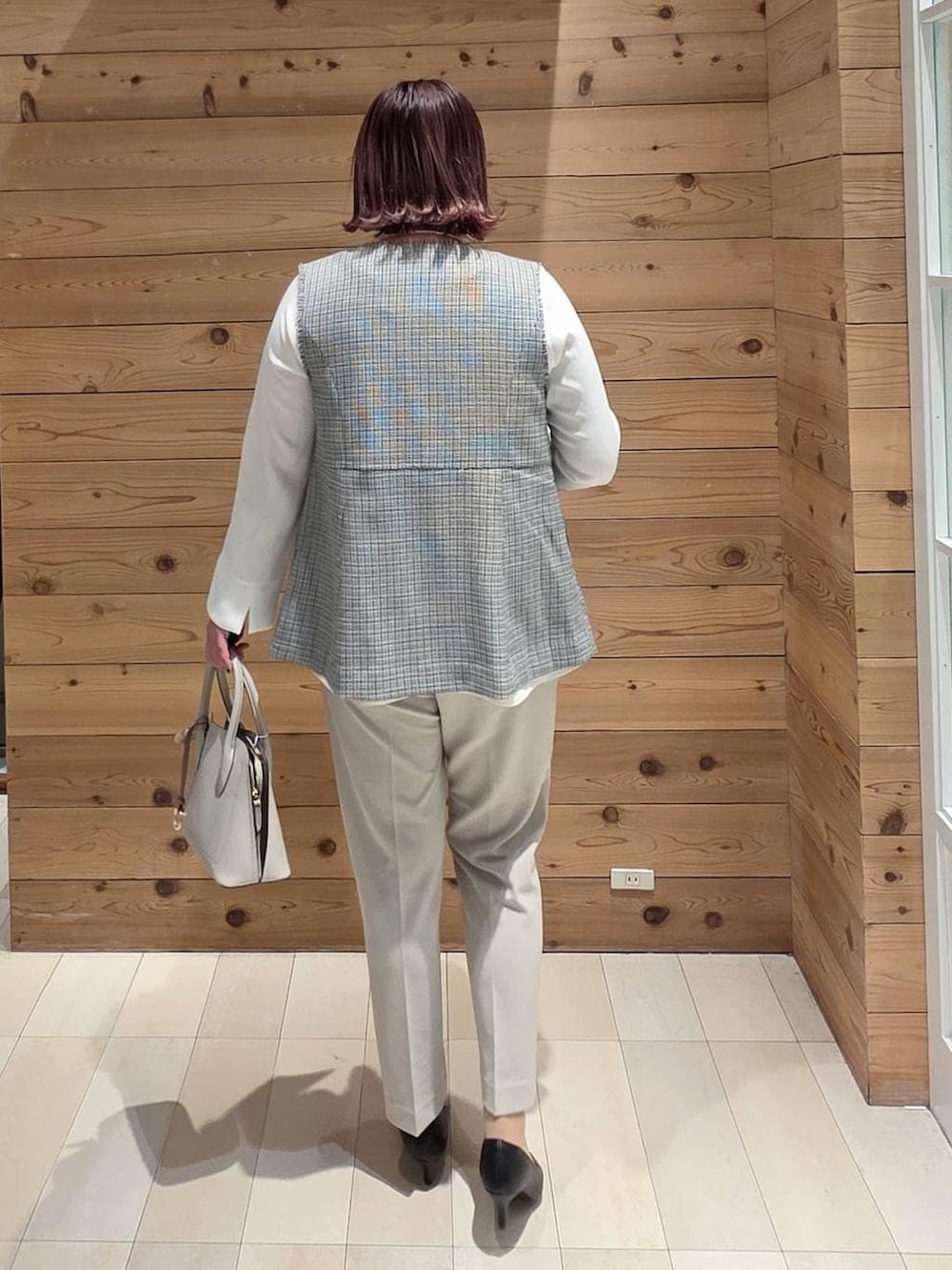 ホワイト系のショルダーバッグ、ブラック系のパンプス、ベージュ系のセットアップを着用したレディースの冬コーディネートの3枚目の写真