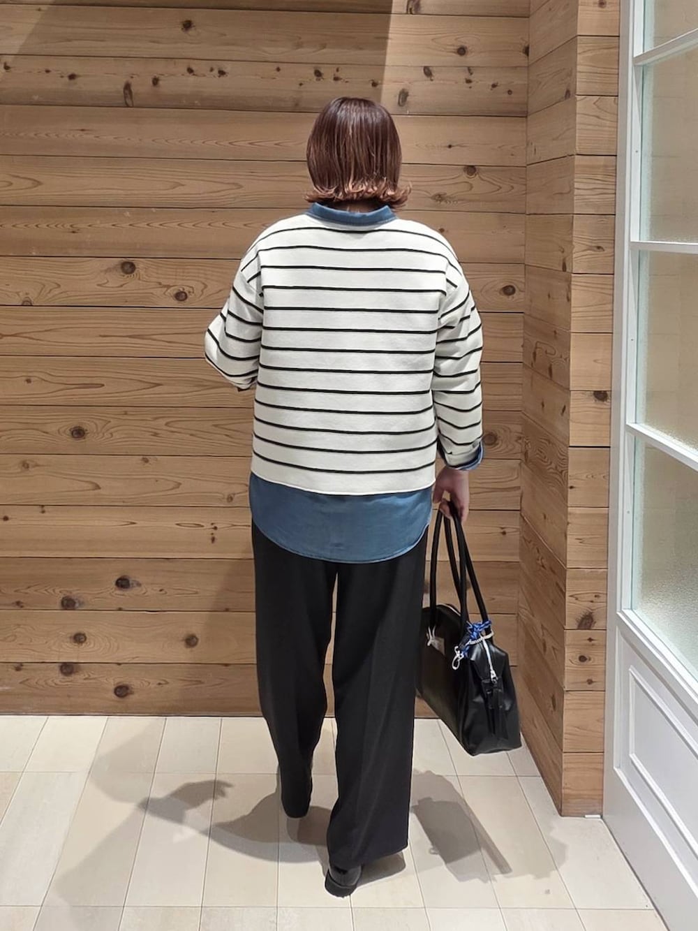 ブラック系のローファー、ブラック系のボストンバッグ、ブルー系のシャツ/ブラウスを着用したレディースの春コーディネートの3枚目の写真