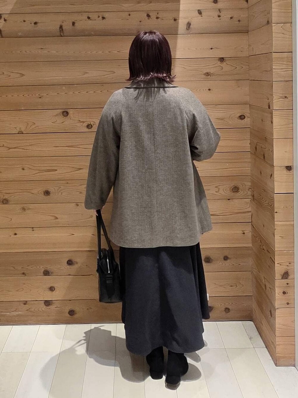 ブラック系のボストンバッグ、ブラウン系のチェスターコート、グレー系のスカートを着用したレディースの冬コーディネートの3枚目の写真