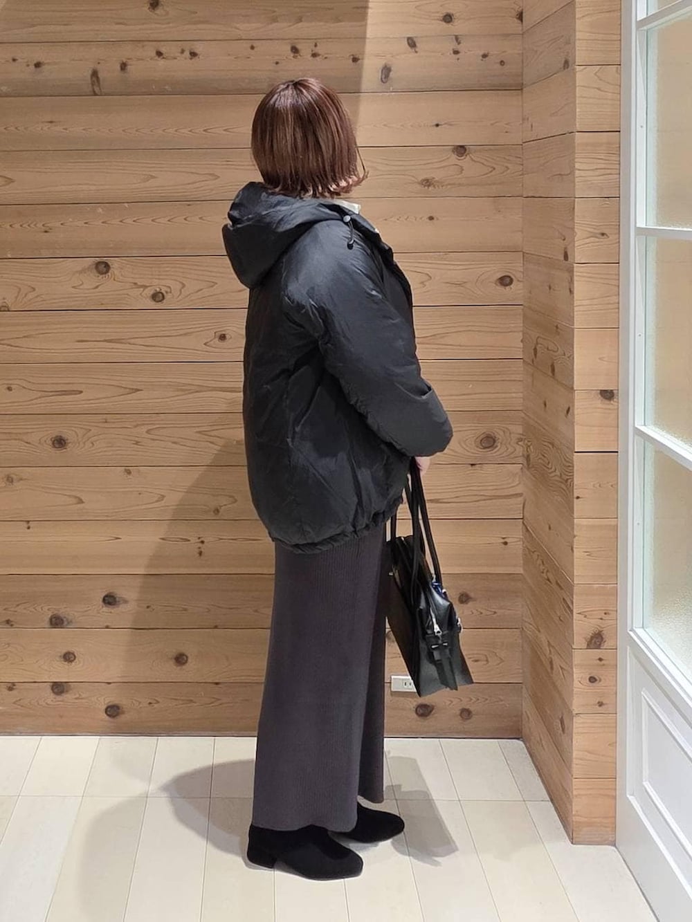 ブラック系のダウンジャケット/コート、ブラック系のボストンバッグ、ホワイト系のシャツ/ブラウスを着用したレディースの秋コーディネートの2枚目の写真