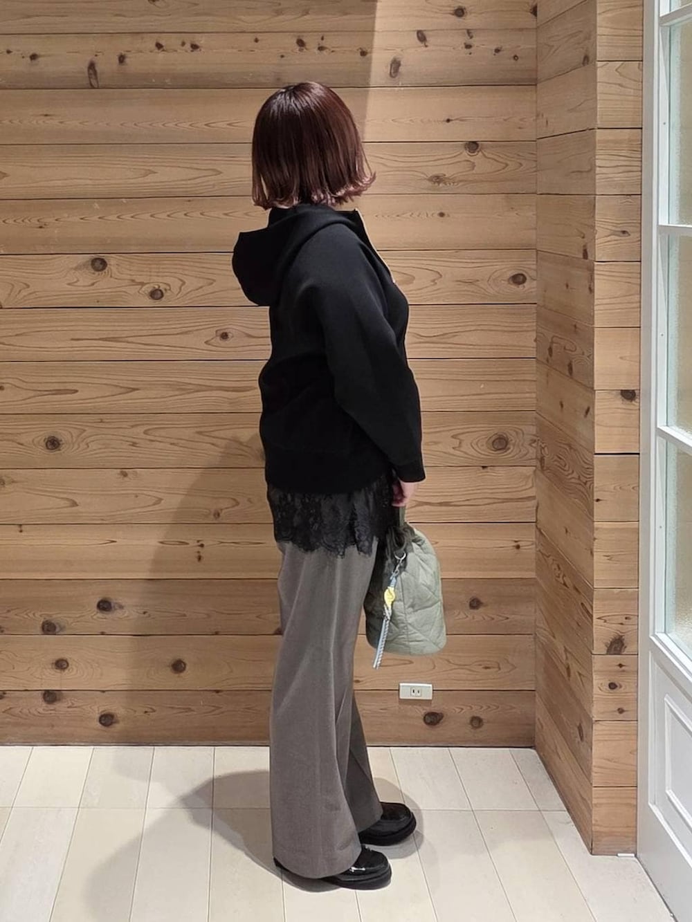 ブラック系のローファー、グリーン系のハンドバッグ、ブラック系のパーカーを着用したレディースの春コーディネートの2枚目の写真