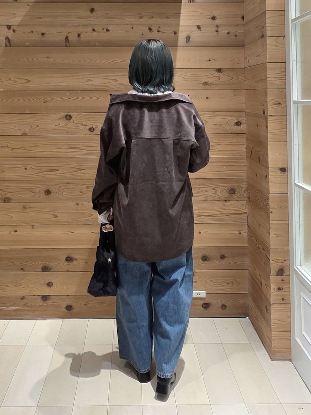 ブルー系のデニムパンツ、オレンジ系のキャミソール、ブラック系のブーツを着用したレディースの秋コーディネートの3枚目の写真