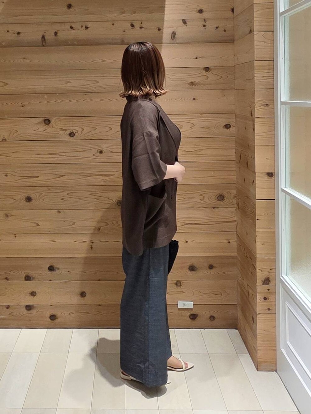 ブラウン系のテーラードジャケット、ブルー系のその他パンツ、ブラック系のクラッチバッグを着用したレディースの夏コーディネートの2枚目の写真