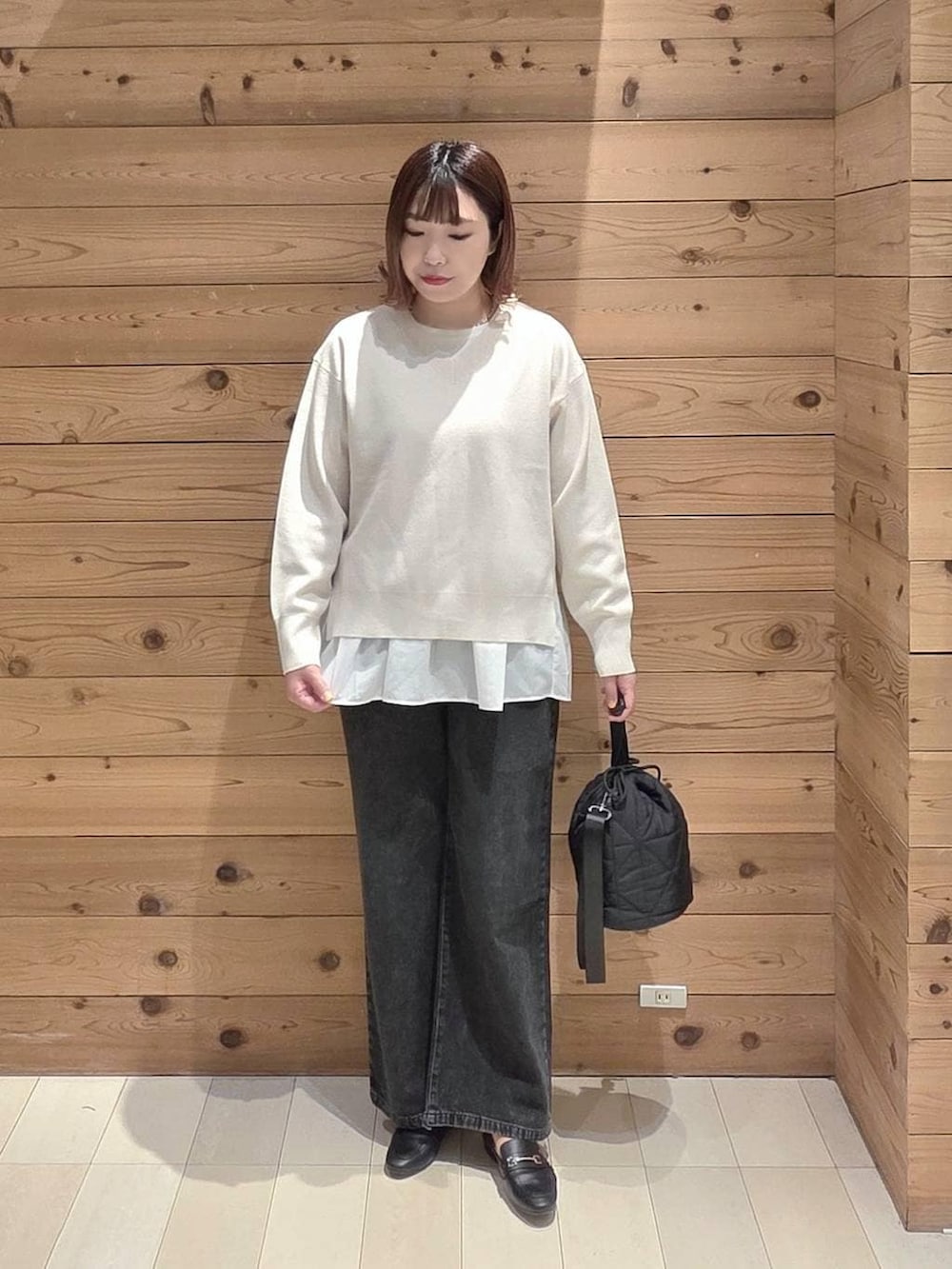 ブラック系のデニムパンツ、ブラック系のハンドバッグ、ベージュ系のマウンテンパーカーを着用したレディースの春コーディネートの4枚目の写真