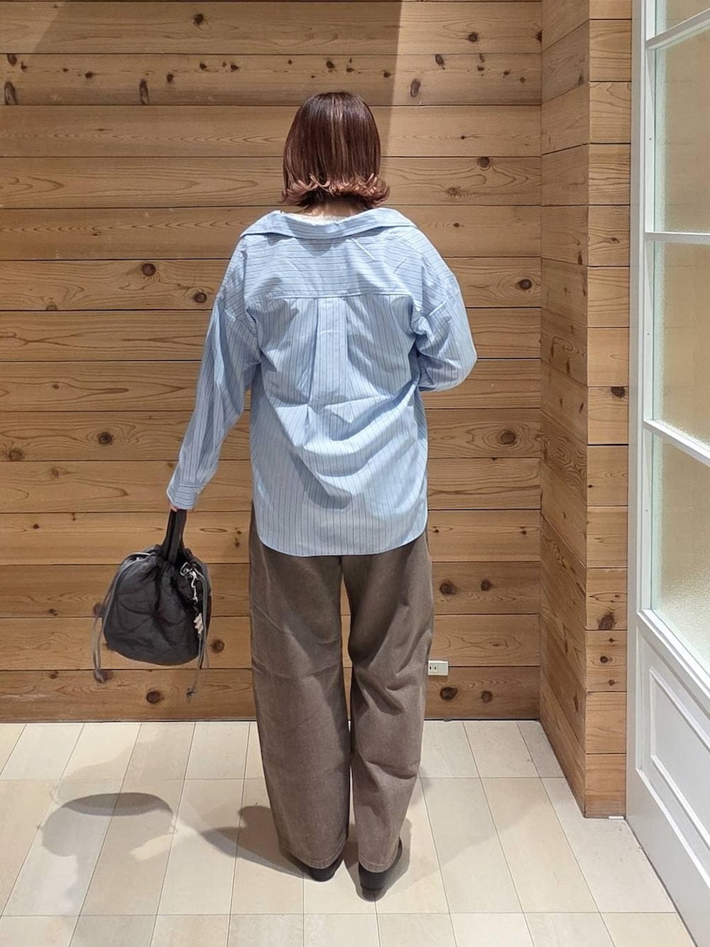 ブラック系のパンプス、ブルー系のシャツ/ブラウス、グレー系のハンドバッグを着用したレディースの春コーディネートの3枚目の写真