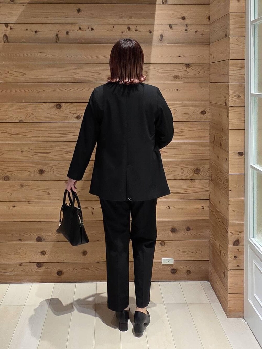 ブラック系のローファー、ブラック系のショルダーバッグ、ブラック系のスラックスを着用したレディースの冬コーディネートの3枚目の写真