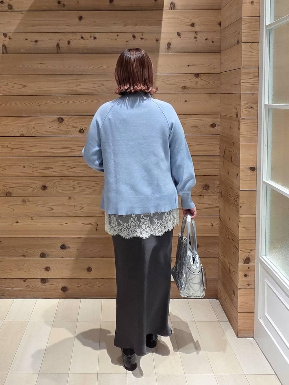 ブラック系のローファー、シルバー系のトートバッグ、ブルー系のニット/セーターを着用したレディースの冬コーディネートの3枚目の写真