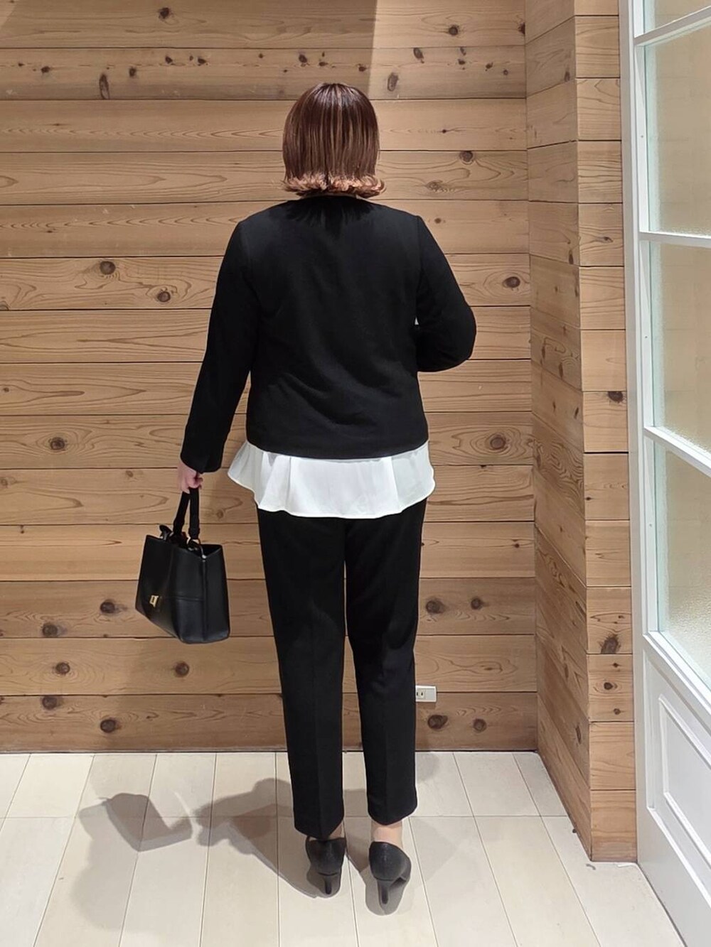 ブラック系のセットアップ、ブラック系のショルダーバッグ、ゴールド系のネックレスを着用したレディースの冬コーディネートの3枚目の写真