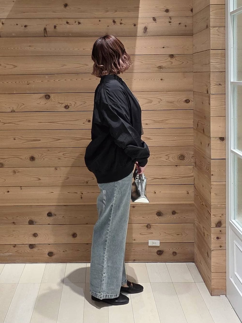 ブラック系のローファー、シルバー系のショルダーバッグ、ブルー系のデニムパンツを着用したレディースの春コーディネートの2枚目の写真