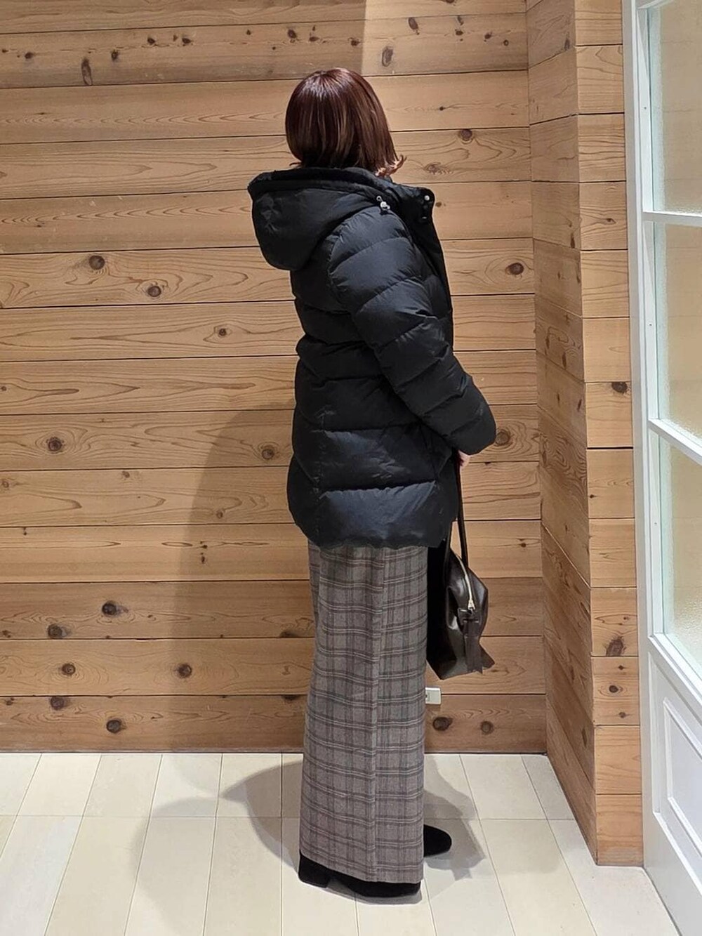 ブラウン系のボストンバッグ、ブラック系のダウンジャケット/コート、ベージュ系のスウェットを着用したレディースの冬コーディネートの2枚目の写真