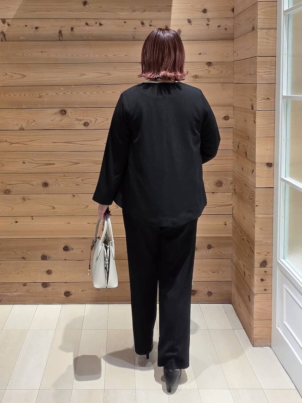 ホワイト系のショルダーバッグ、ブラック系のパンプス、ブラック系のセットアップを着用したレディースの冬コーディネートの3枚目の写真