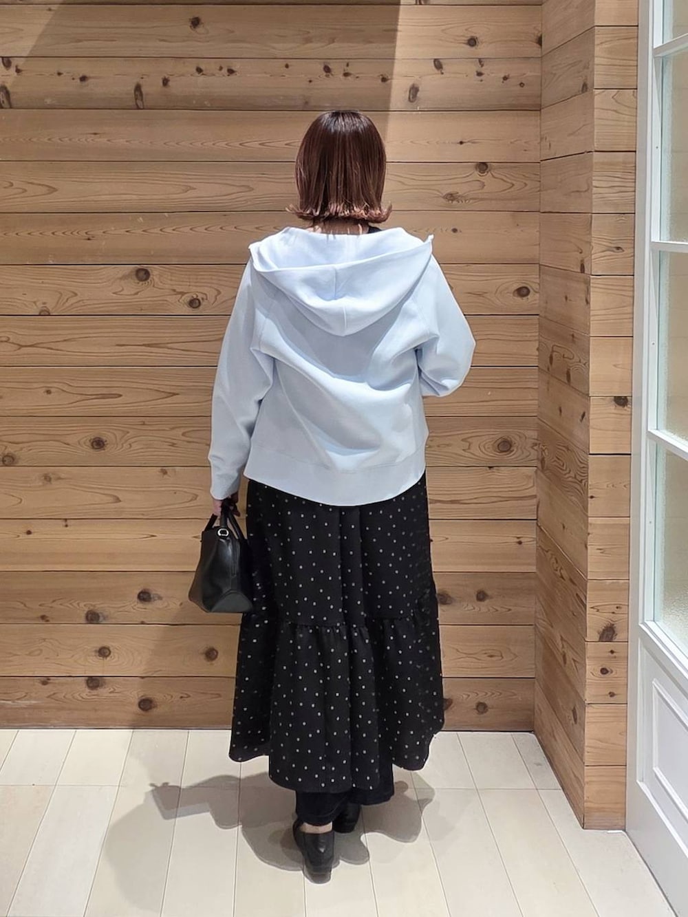 ブラック系のローファー、ブラック系のショルダーバッグ、ブルー系のデニムパンツを着用したレディースの春コーディネートの3枚目の写真