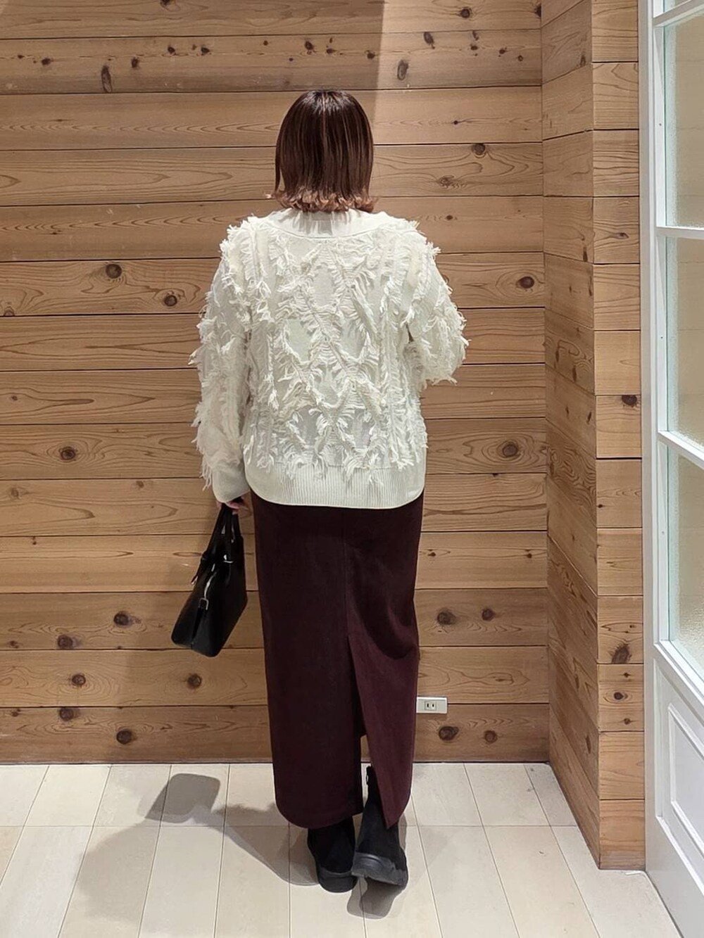 ブラック系のショルダーバッグ、ブラウン系のチェスターコート、レッド系のスカートを着用したレディースの冬コーディネートの3枚目の写真