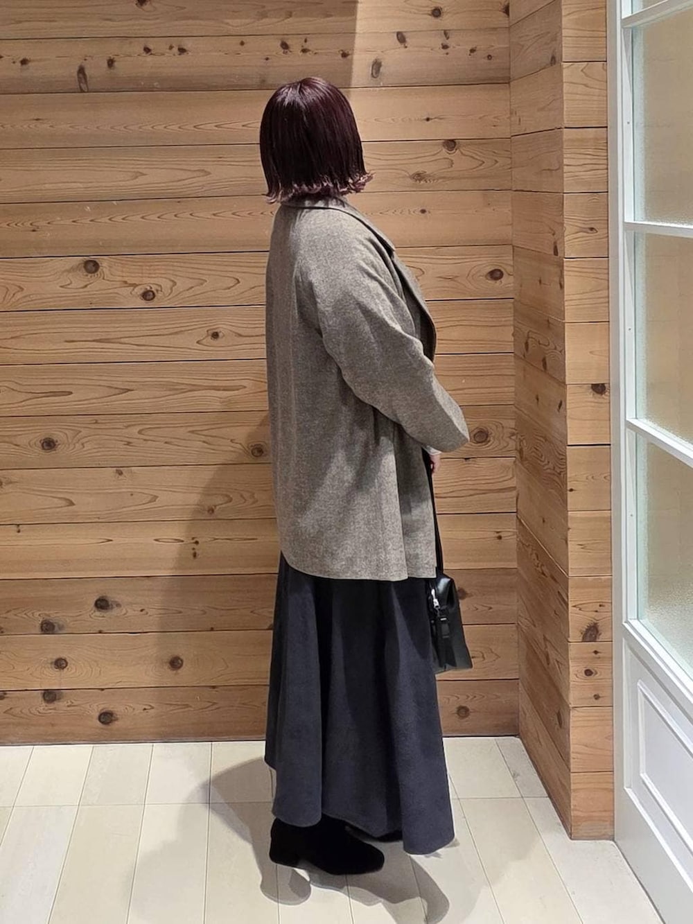 ブラック系のボストンバッグ、ブラウン系のチェスターコート、グレー系のスカートを着用したレディースの冬コーディネートの2枚目の写真