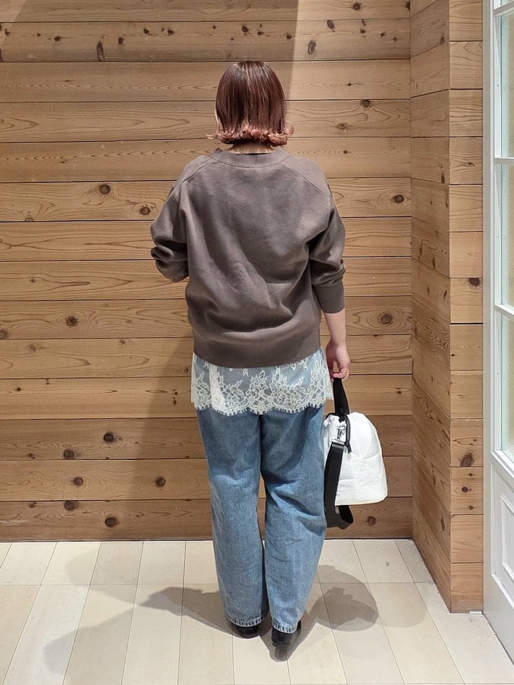 ブラック系のバレエシューズ、ホワイト系のハンドバッグ、ブルー系のデニムパンツを着用したレディースの春コーディネートの3枚目の写真