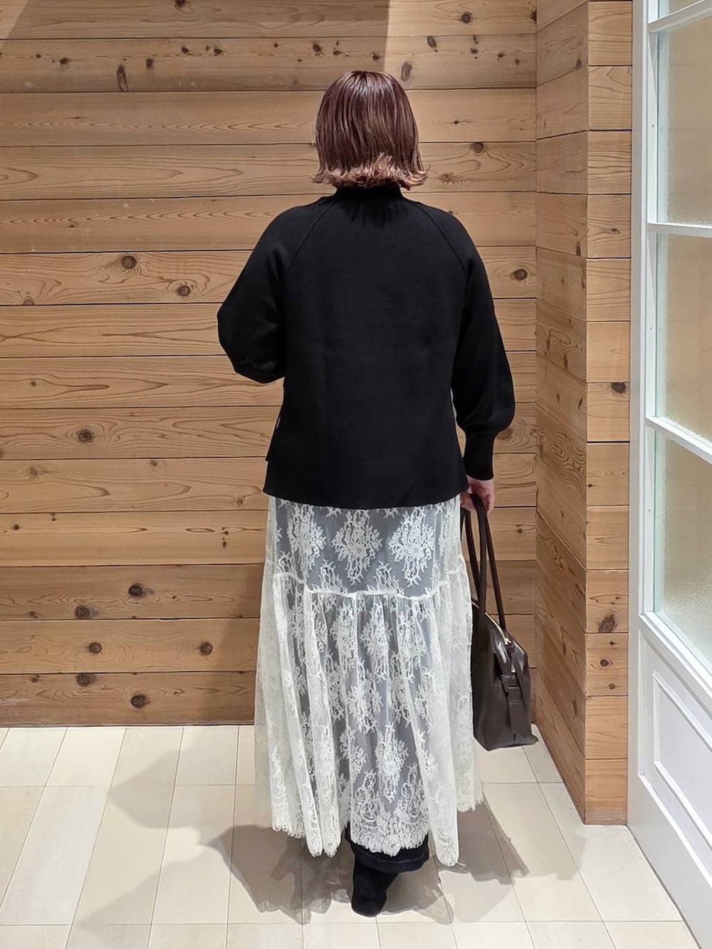 ブラウン系のボストンバッグ、ブルー系のデニムパンツ、ブラウン系のチェスターコートを着用したレディースの冬コーディネートの3枚目の写真