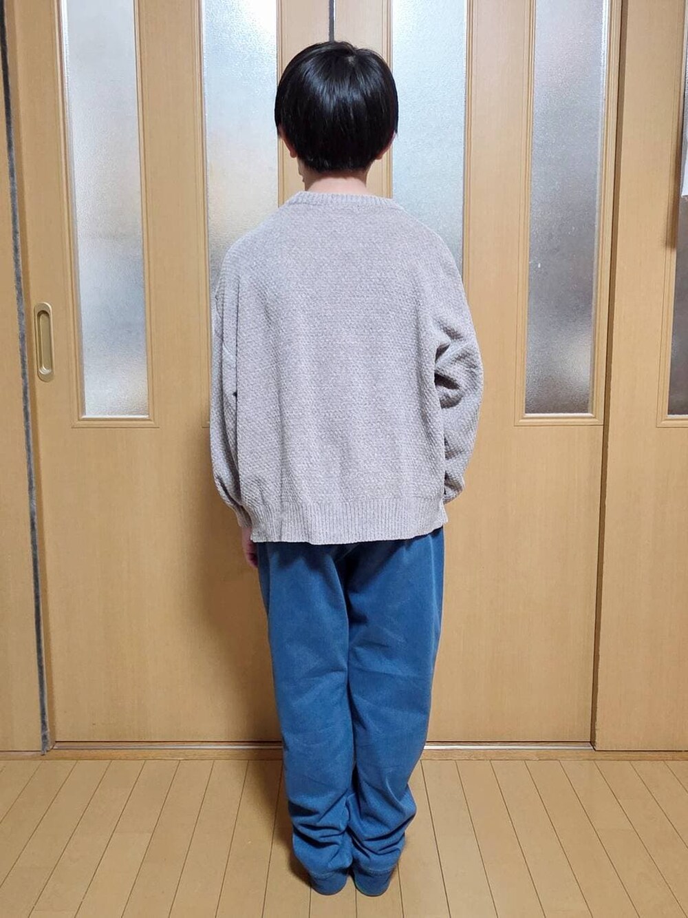 ベージュ系のニット/セーター、ブルー系のデニムパンツを着用したキッズの冬コーディネートの3枚目の写真