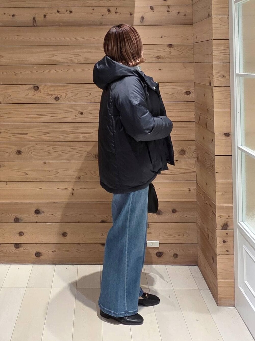 ブラック系のローファー、ブラック系のショルダーバッグ、ブルー系のダウンジャケット/コートを着用したレディースの冬コーディネートの2枚目の写真