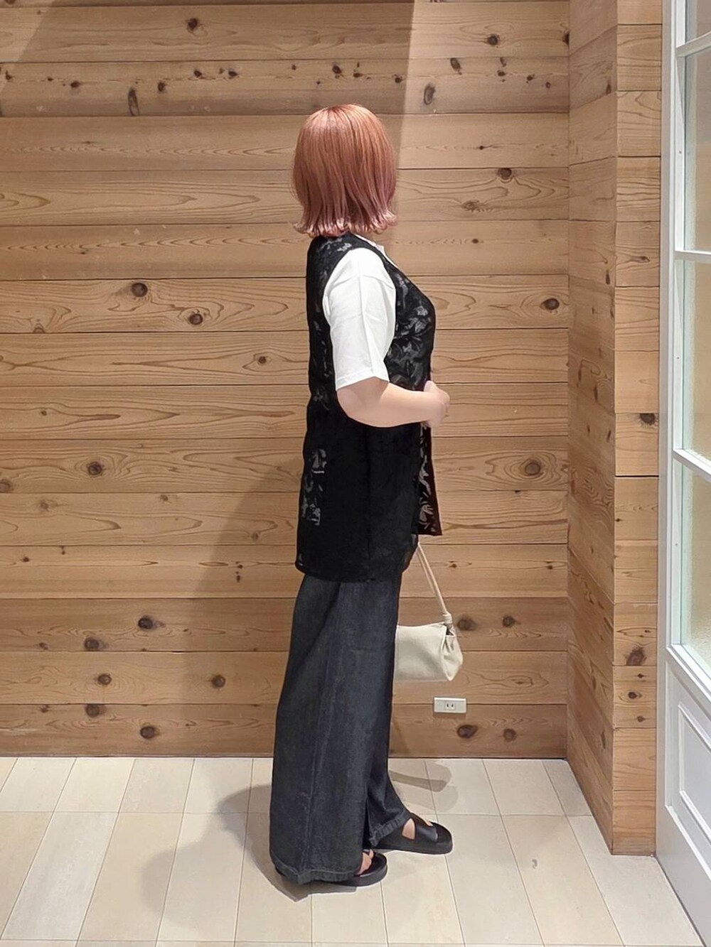 ブラック系のベスト、ベージュ系のショルダーバッグ、ホワイト系のTシャツ/カットソーを着用したレディースの夏コーディネートの2枚目の写真