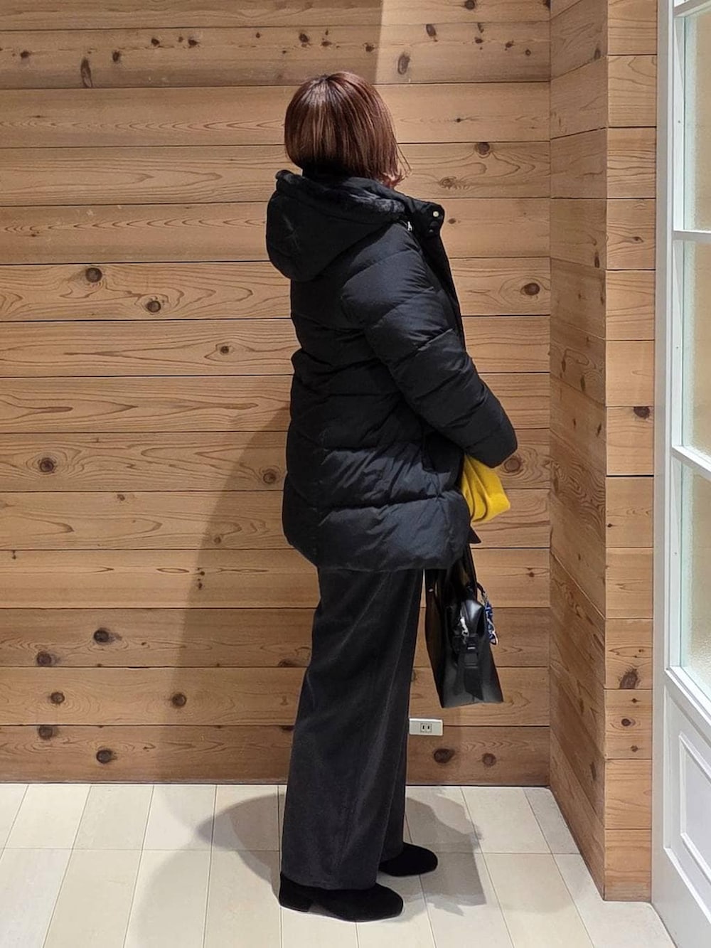 ブラック系のボストンバッグ、ブラック系のダウンジャケット/コート、ホワイト系のシャツ/ブラウスを着用したレディースの冬コーディネートの2枚目の写真