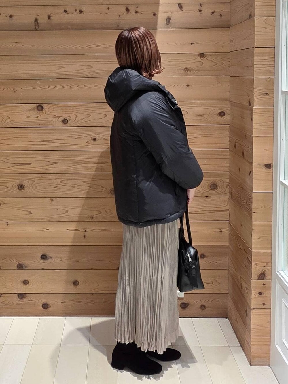 ブラック系のダウンジャケット/コート、ブラック系のボストンバッグ、ホワイト系のTシャツ/カットソーを着用したレディースの冬コーディネートの2枚目の写真