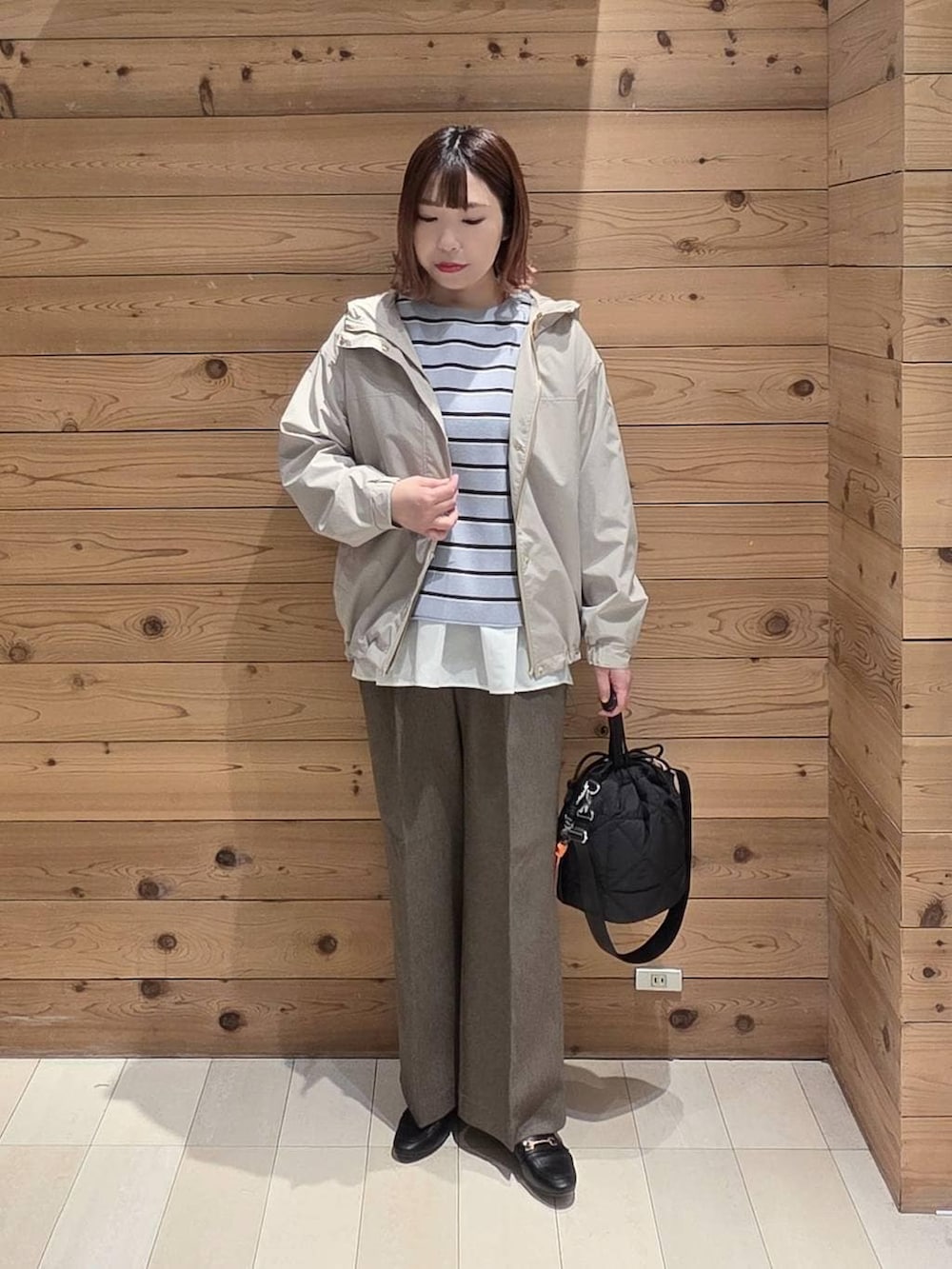 ブラック系のローファー、ブラック系のハンドバッグ、ベージュ系のマウンテンパーカーを着用したレディースの春コーディネートの4枚目の写真