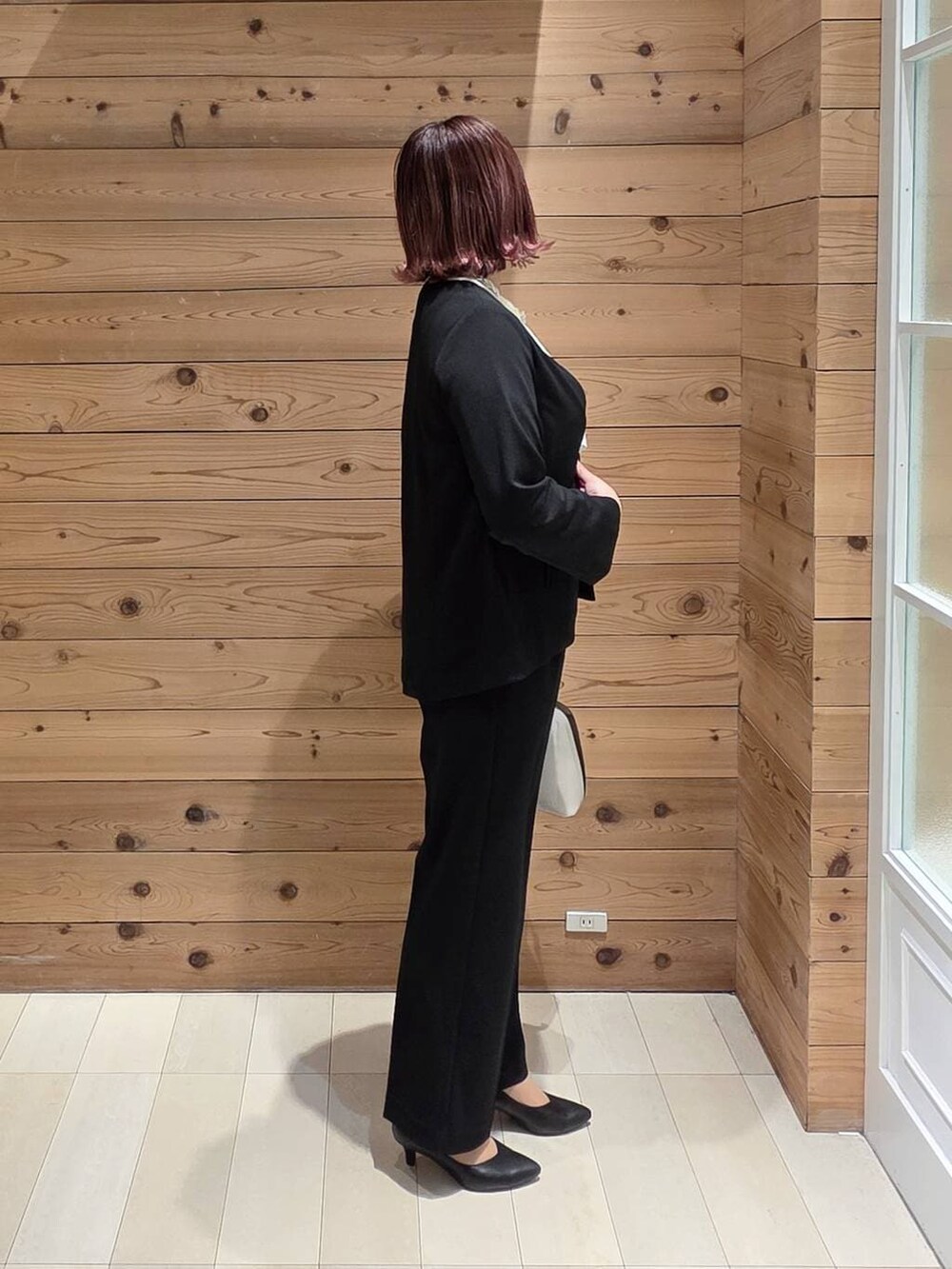 ホワイト系のショルダーバッグ、ブラック系のパンプス、ブラック系のセットアップを着用したレディースの冬コーディネートの2枚目の写真