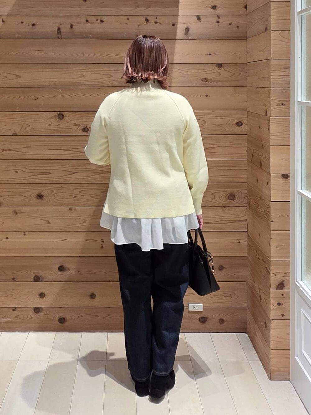 ブラック系のショルダーバッグ、ブルー系のデニムパンツ、ブラウン系のチェスターコートを着用したレディースの冬コーディネートの3枚目の写真