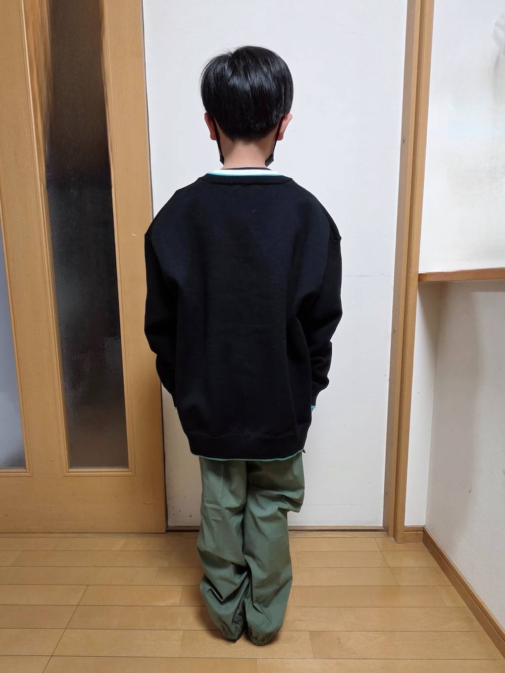 グリーン系のカーゴパンツ、ホワイト系のTシャツ/カットソー、ブラック系のニット/セーターを着用したキッズの春コーディネートの3枚目の写真