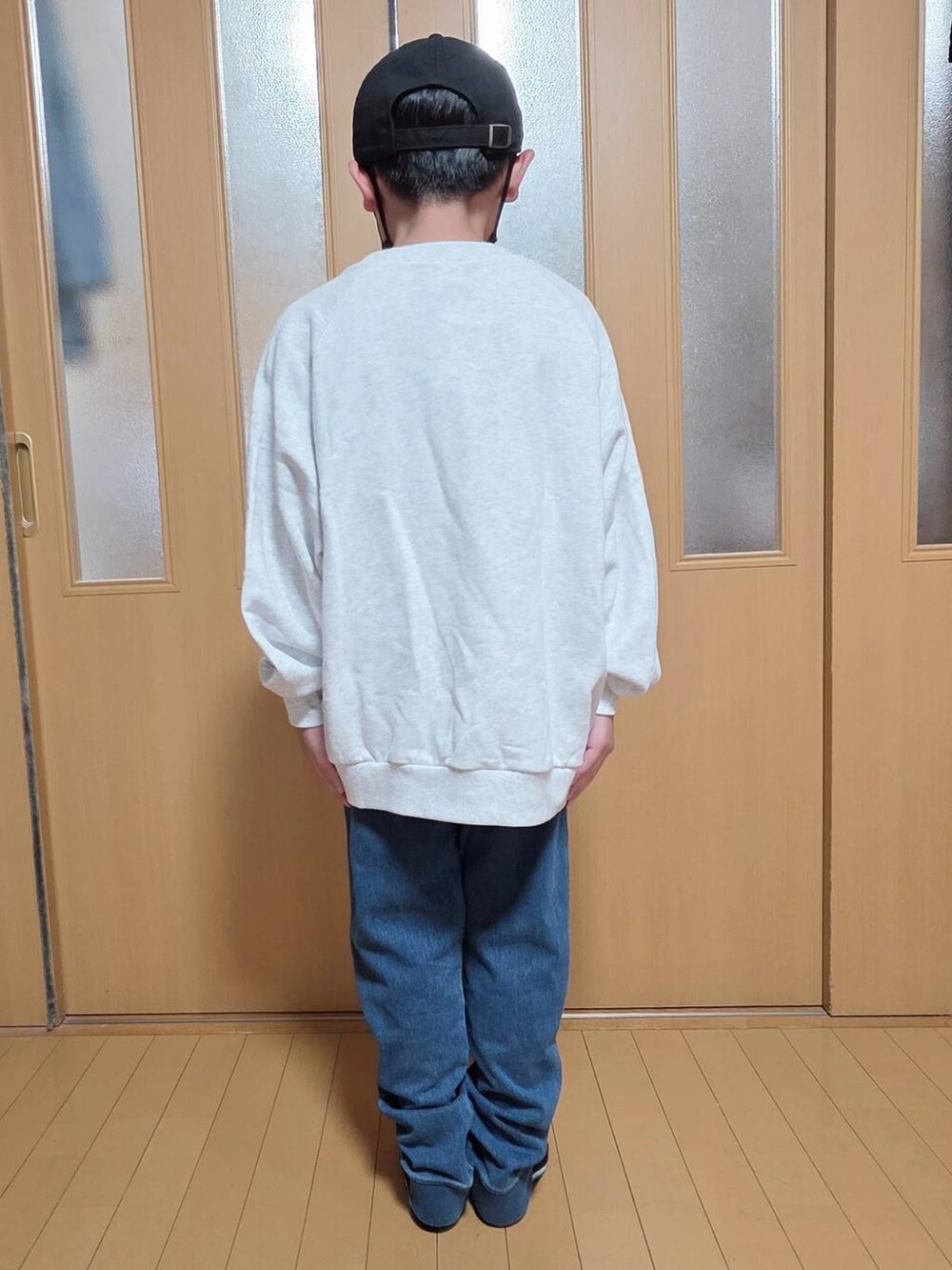 ブルー系のデニムパンツ、グレー系のスウェット、ブラック系のキャップを着用したキッズの秋コーディネートの3枚目の写真