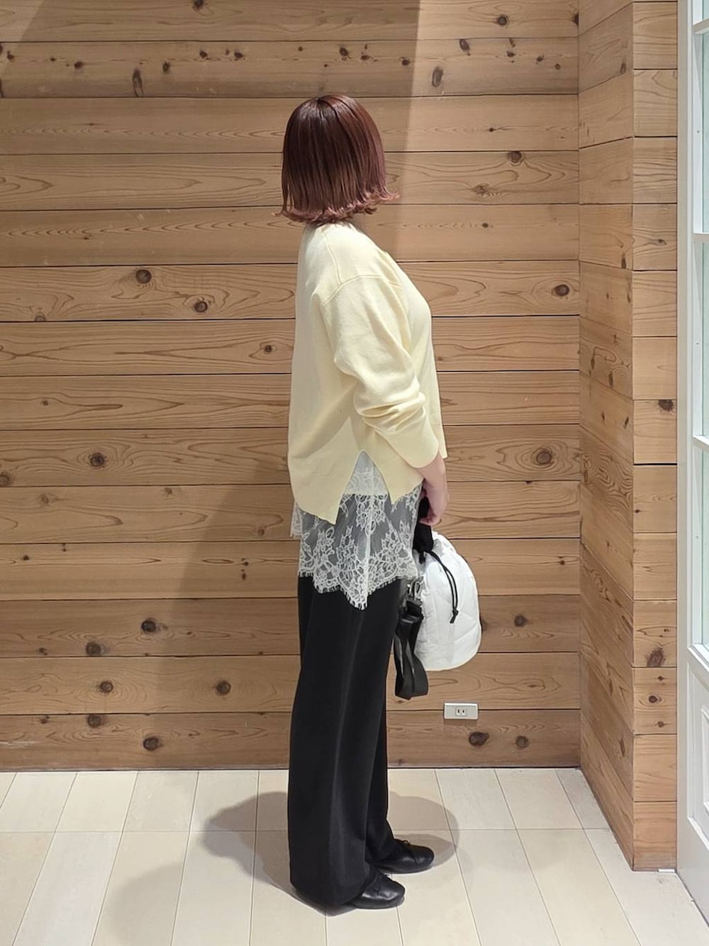 ブラック系のバレエシューズ、ホワイト系のハンドバッグ、イエロー系のニット/セーターを着用したレディースの春コーディネートの2枚目の写真