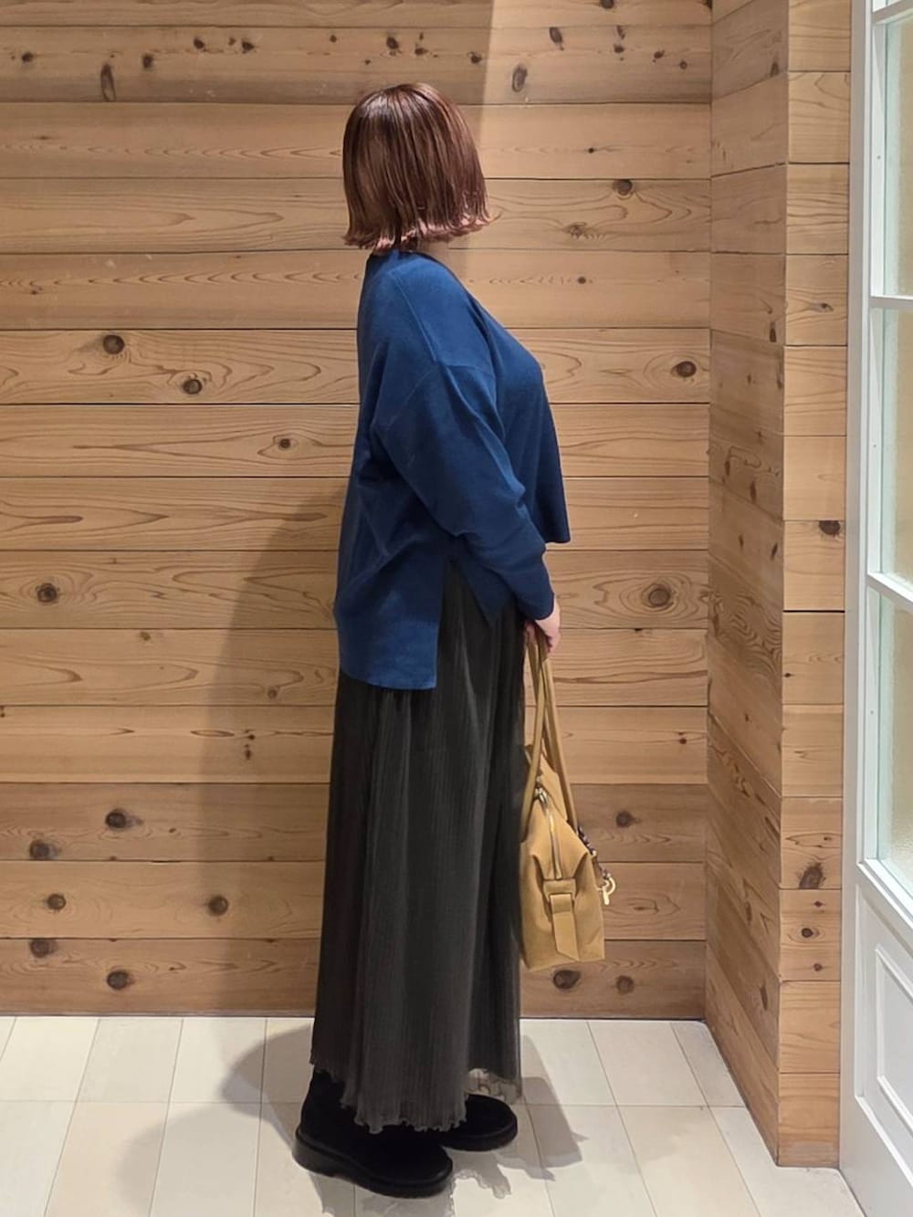 ブラック系のボストンバッグ、ブラック系のダウンジャケット/コート、ブルー系のニット/セーターを着用したレディースの秋コーディネートの2枚目の写真