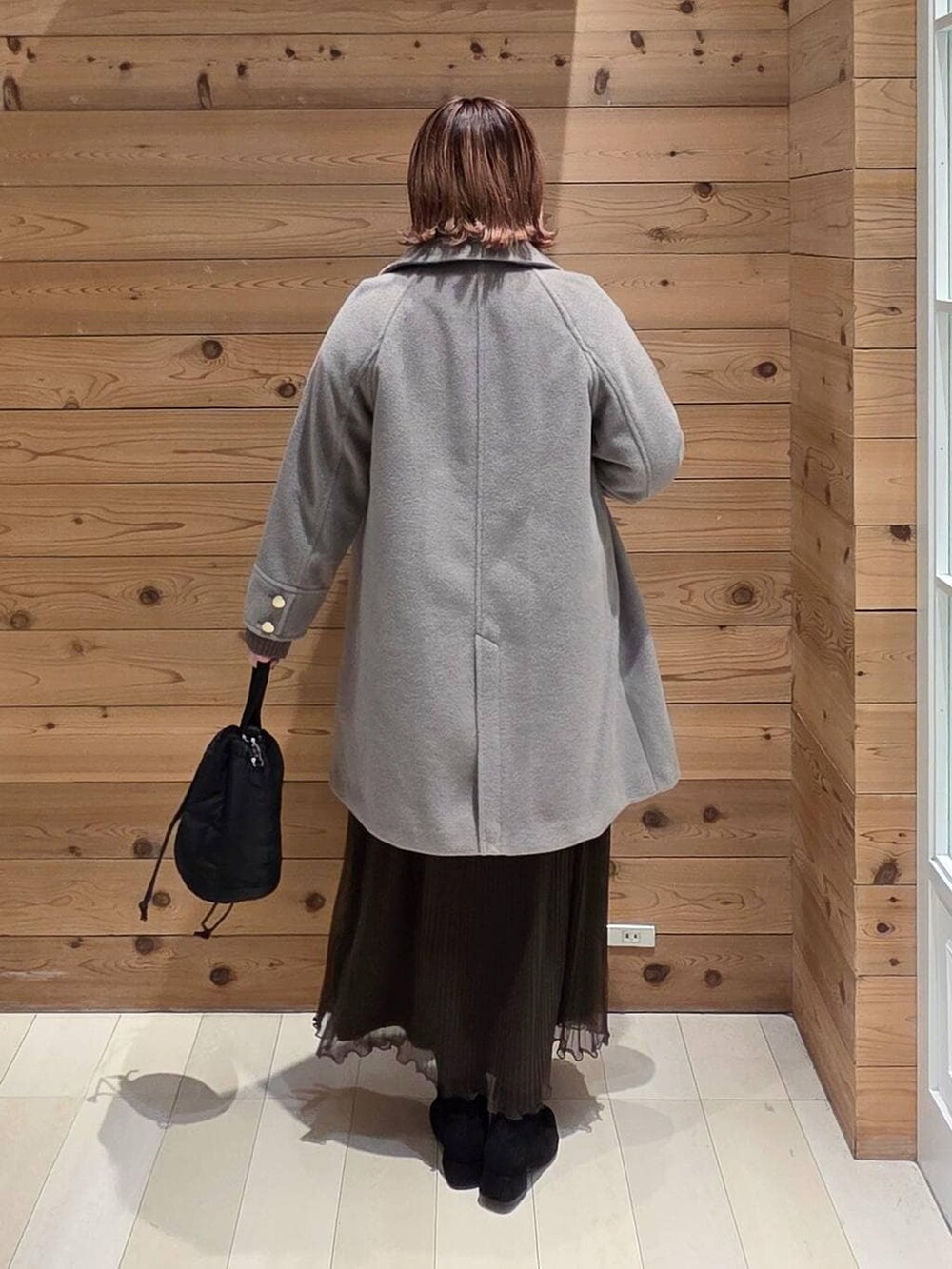 ベージュ系のチェスターコート、ブラック系のハンドバッグ、ホワイト系のTシャツ/カットソーを着用したレディースの冬コーディネートの3枚目の写真