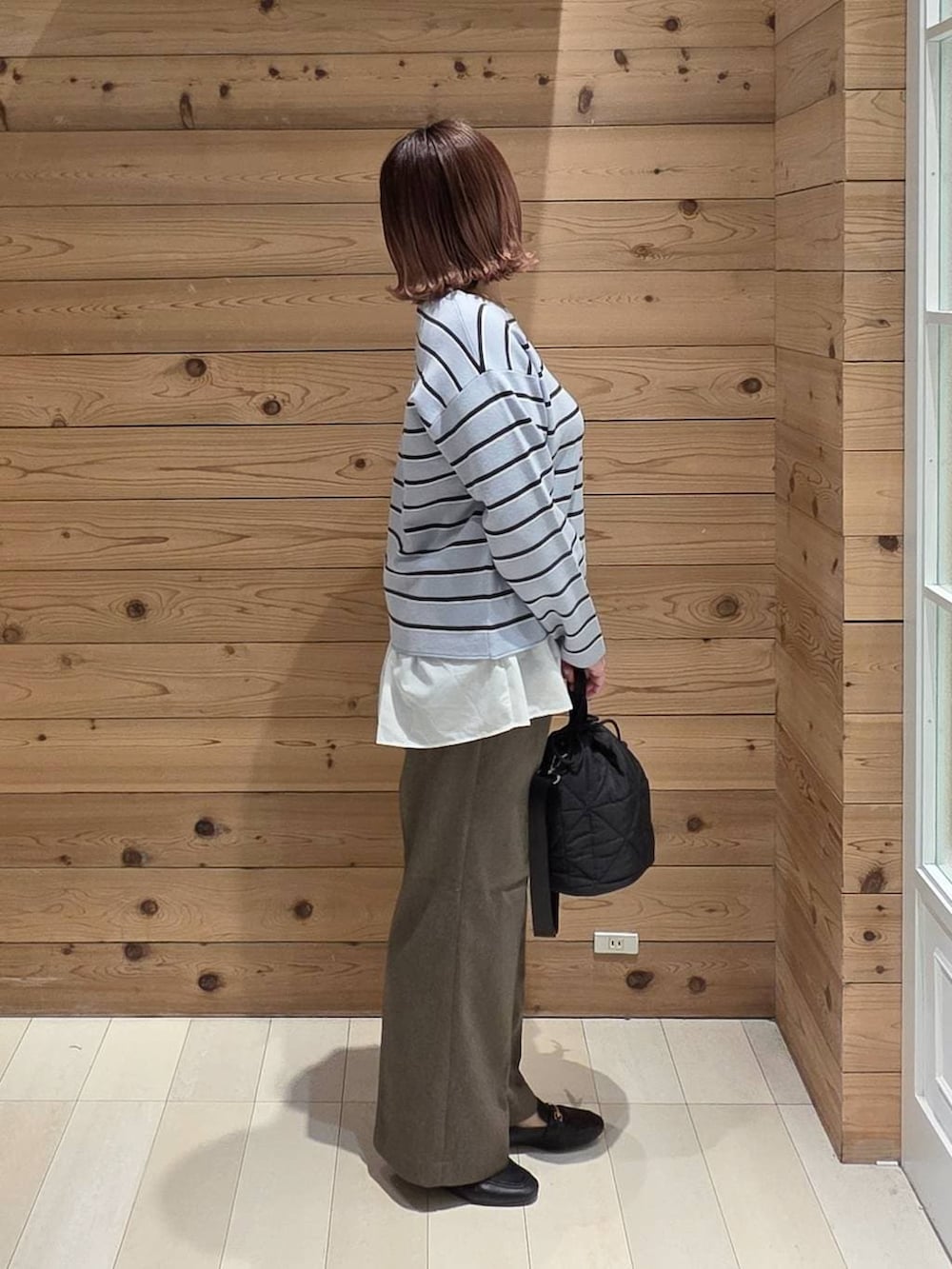 ブラック系のローファー、ブラック系のハンドバッグ、ベージュ系のマウンテンパーカーを着用したレディースの春コーディネートの2枚目の写真