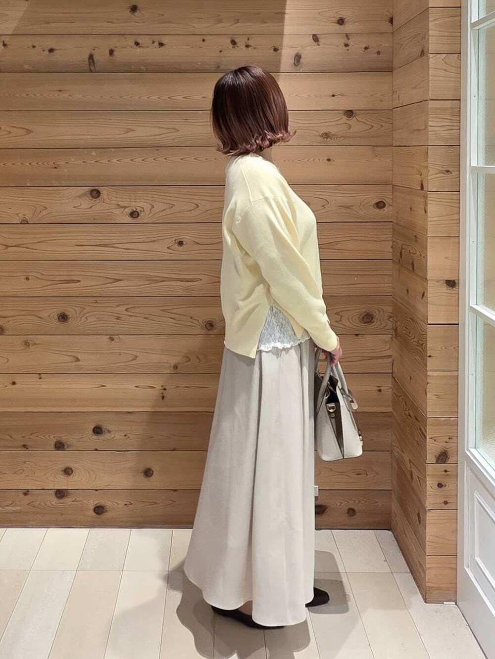 ブラック系のパンプス、ホワイト系のショルダーバッグ、ベージュ系のスカートを着用したレディースの春コーディネートの2枚目の写真