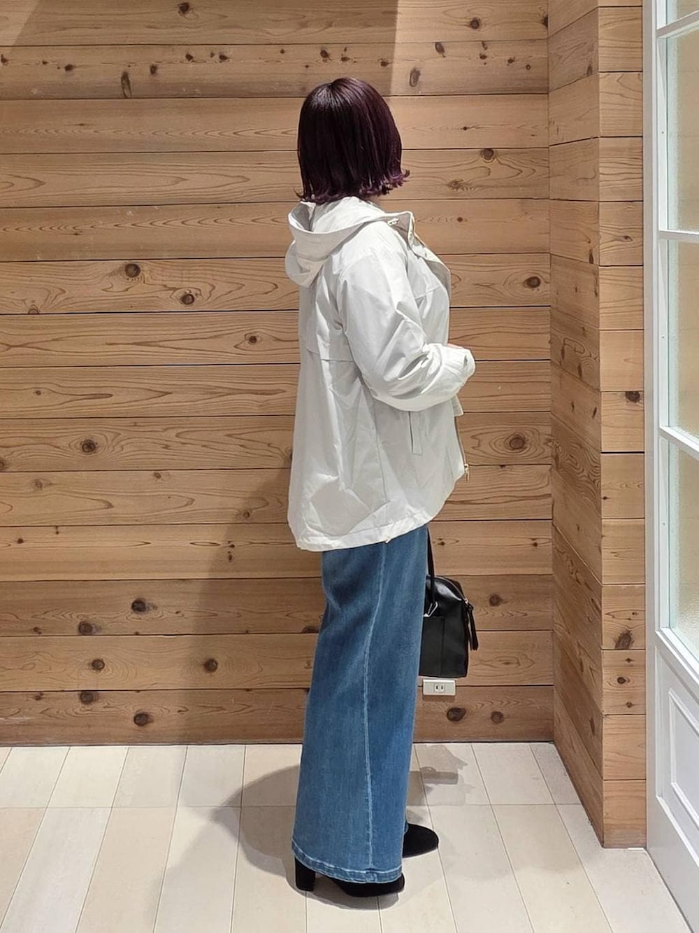 ホワイト系のマウンテンパーカー、ベージュ系のニット/セーター、ブラック系のボストンバッグを着用したレディースの冬コーディネートの2枚目の写真